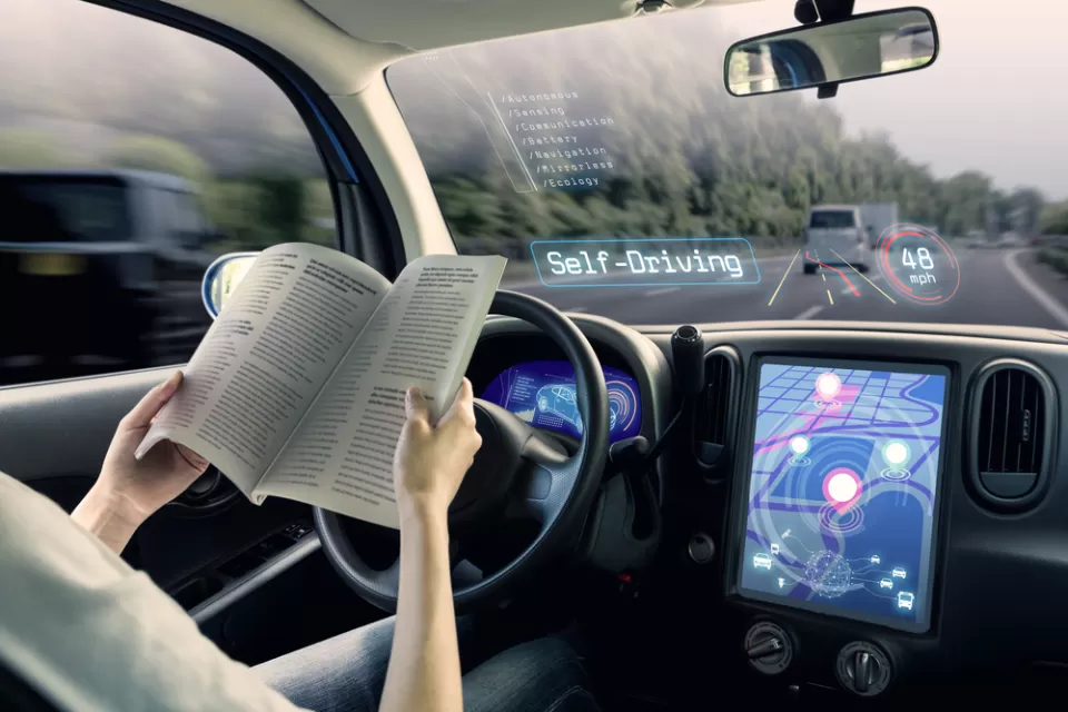 Rendering of autonomous vehicle with woman reading at the wheel